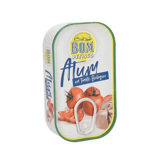 A can of BOM Petisco Atlóm organic tomato soup on a transparent checkerboard background. The can features a white label with green and yellow borders, blue script text, and illustrations of fresh tomatoes and sliced rotisserie chicken.